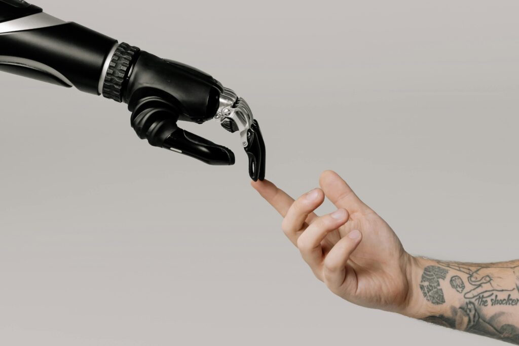 pexels-photo-6153354-6153354 A human hand with tattoos reaching out to a robotic hand on a white background, Inteligência Artificial no Mercado Financeiro